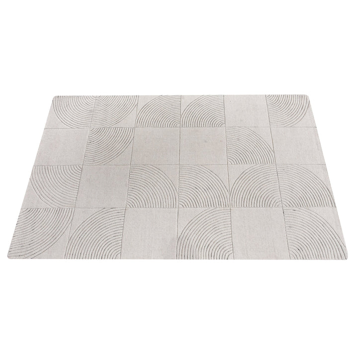 Seashell handwoven ivory wool rug with carved concentric arc tiles, in a bedroom