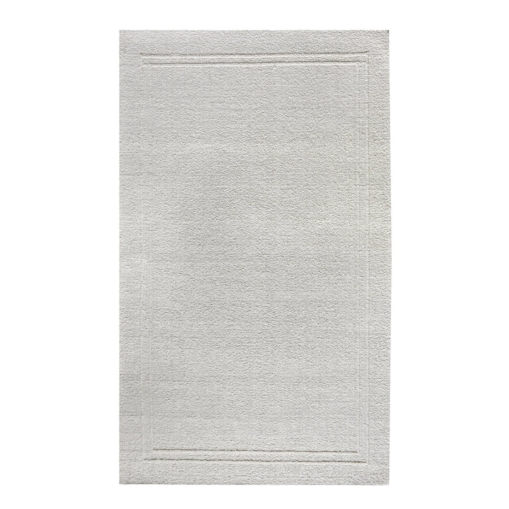 Margin handwoven ivory wool rug with a raised tonal border, in a living room