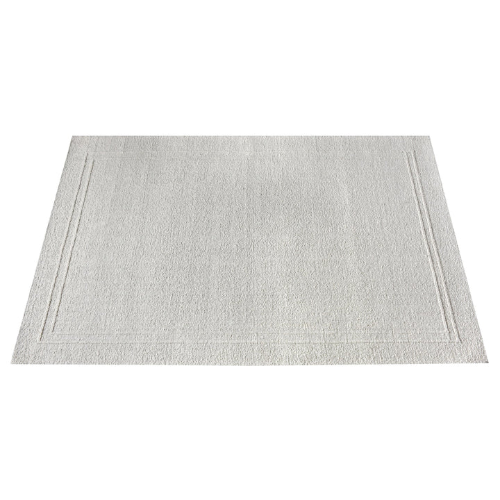 Margin handwoven ivory wool rug with a raised tonal border, in a living room