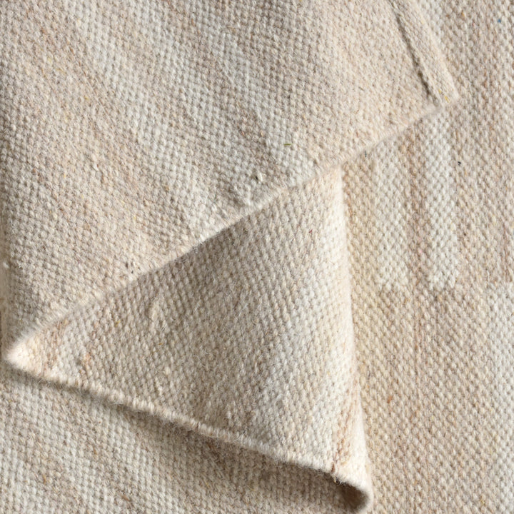 Parat handwoven wool rug in cream and oatmeal with vertical block stripes, in a bedroom