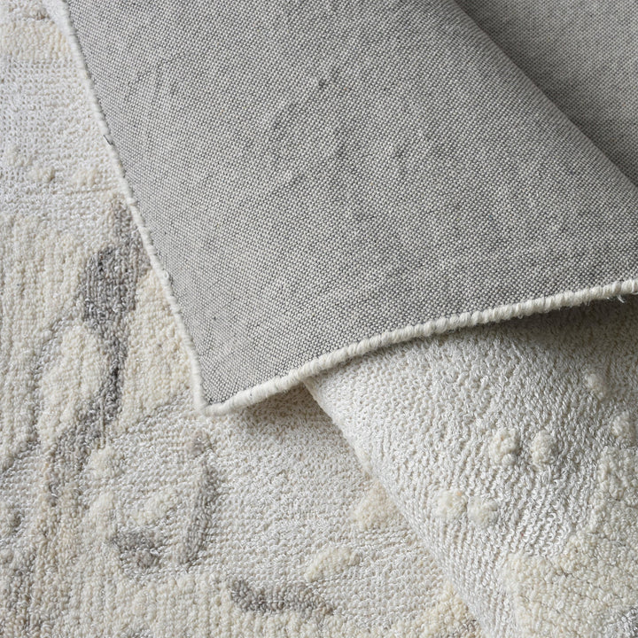 Daali handwoven wool and viscose rug with grey carved branch lines on ivory, in a bedroom