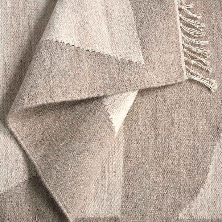 Chhatri handwoven wool rug with bold ivory and beige arch blocks, in a living room