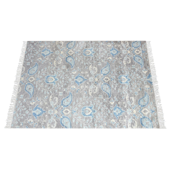 Kairi hand-knotted wool rug with blue paisley on a distressed taupe ground, in a living room