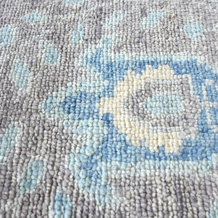 Kairi hand-knotted wool rug with blue paisley on a distressed taupe ground, in a living room