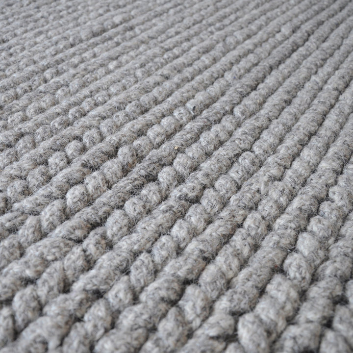 Dor handwoven chunky wool rug in charcoal, woven in thick cords, in a living room