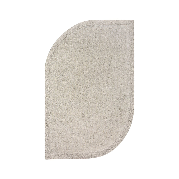 Gol handwoven wool rug in plain cream with a soft cut pile and a curved edge, in a nursery