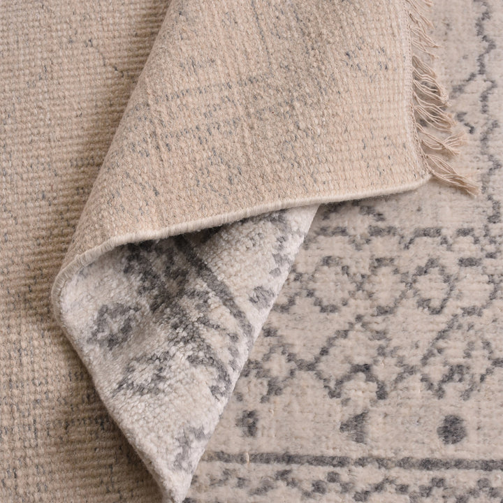 Phatak hand-knotted wool rug with an ivory diamond lattice and grey border, in a dining room