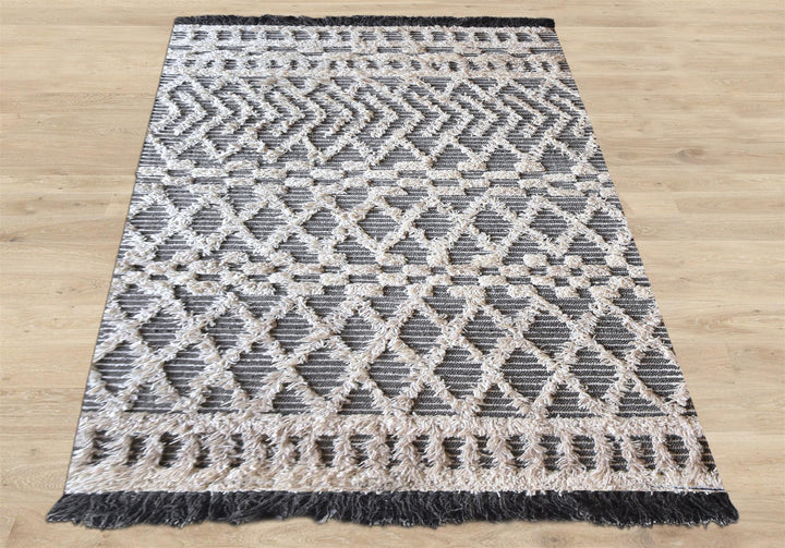 Tassel tufted wool rug with charcoal and ivory chevrons and shaggy bands, in a bedroom