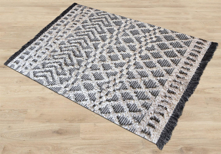 Tassel tufted wool rug with charcoal and ivory chevrons and shaggy bands, in a bedroom
