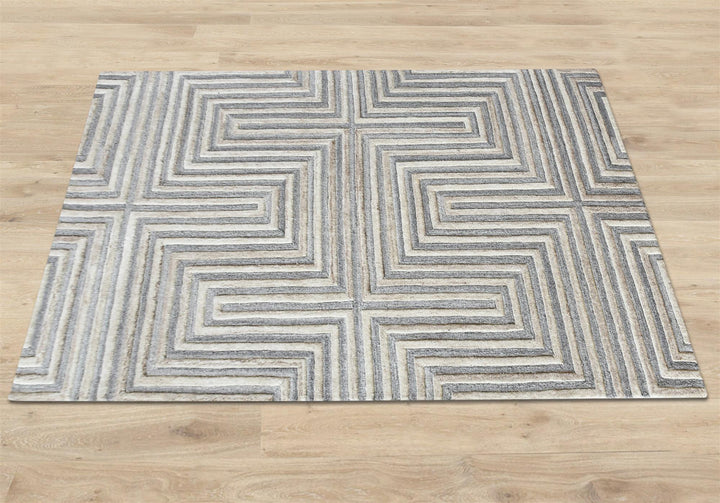 Raasta hand-tufted sand beige wool rug with carved concentric maze lines, in a living room
