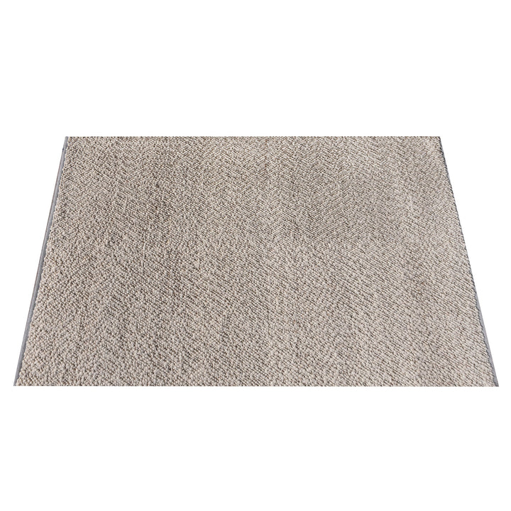 Mitti handwoven wool rug with a nubby looped weave in warm beige and brown, in a living room
