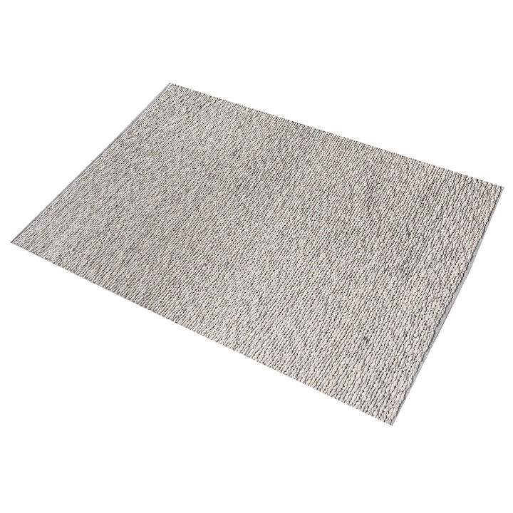Rassi handwoven wool rug with a chunky braided weave in ivory, oatmeal and grey, in a living room