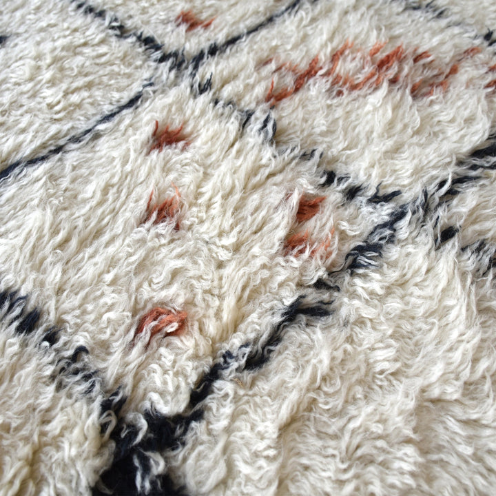 Kesar hand-knotted New Zealand wool shag rug in cream with a black diamond lattice and rust, in a bedroom
