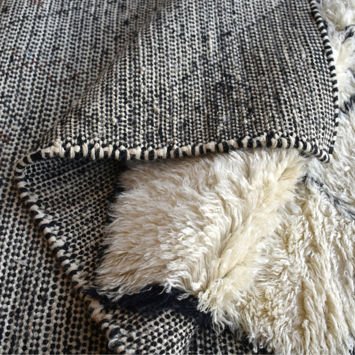 Kesar hand-knotted New Zealand wool shag rug in cream with a black diamond lattice and rust, in a bedroom