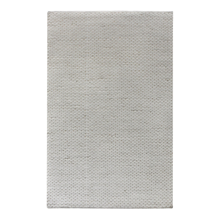 Kankar handwoven wool and jute rug in pale ivory-grey with a pebbled loop weave, in a bedroom