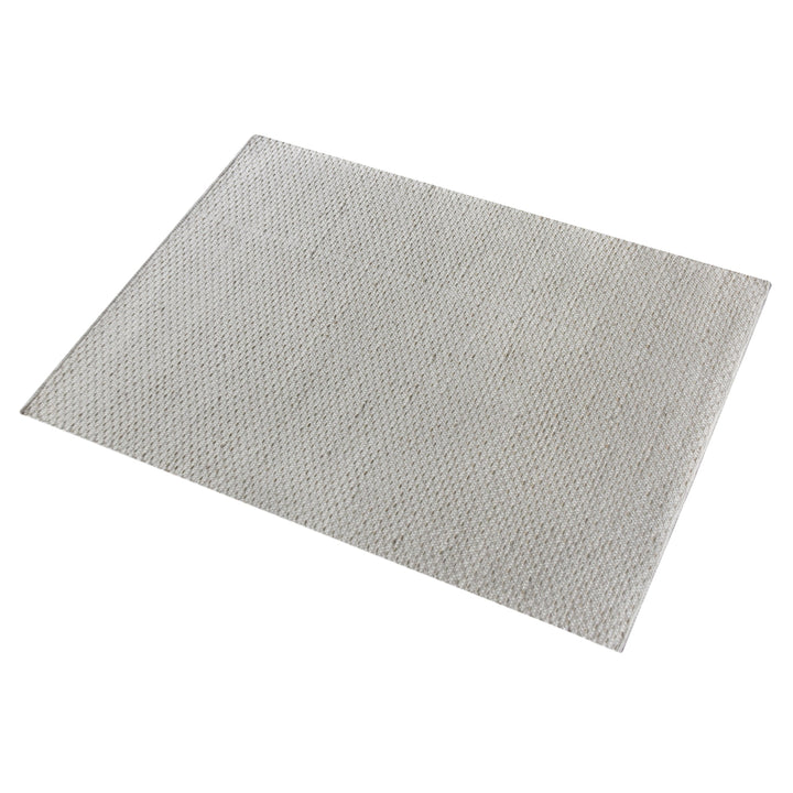 Kankar handwoven wool and jute rug in pale ivory-grey with a pebbled loop weave, in a bedroom