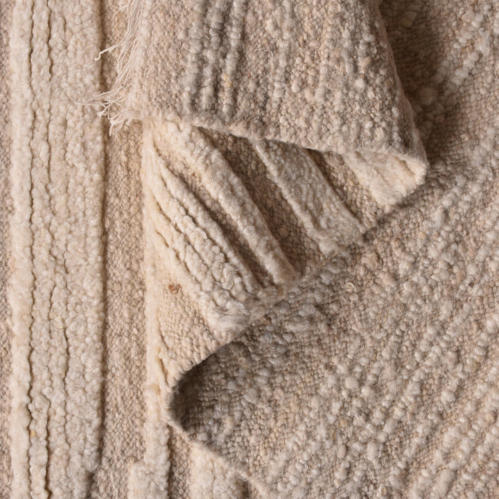 Pankti hand-knotted NZ wool rug in cream and oat with carved vertical stripes, in a dining room