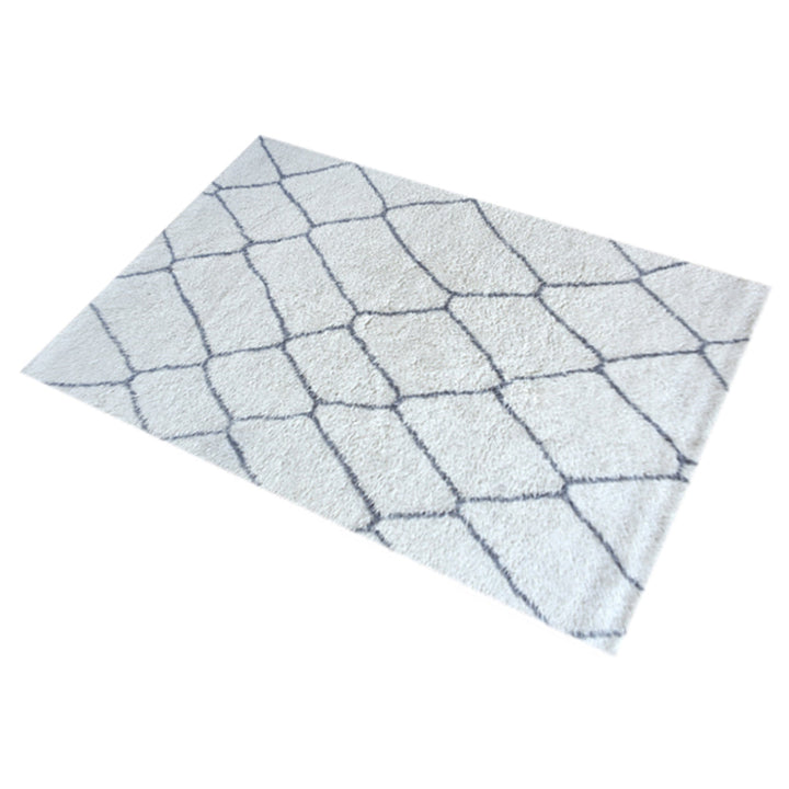 Kohra tufted New Zealand wool rug with a grey diamond lattice on white, in a living room