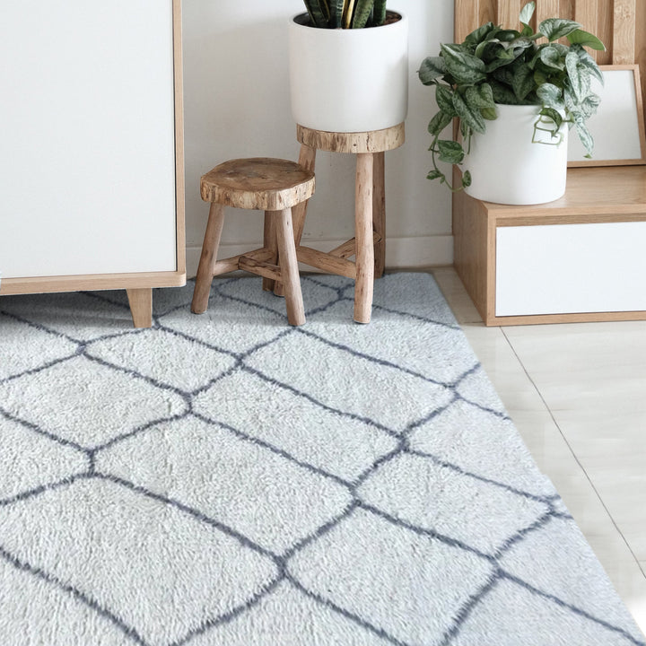Kohra tufted New Zealand wool rug with a grey diamond lattice on white, in a living room