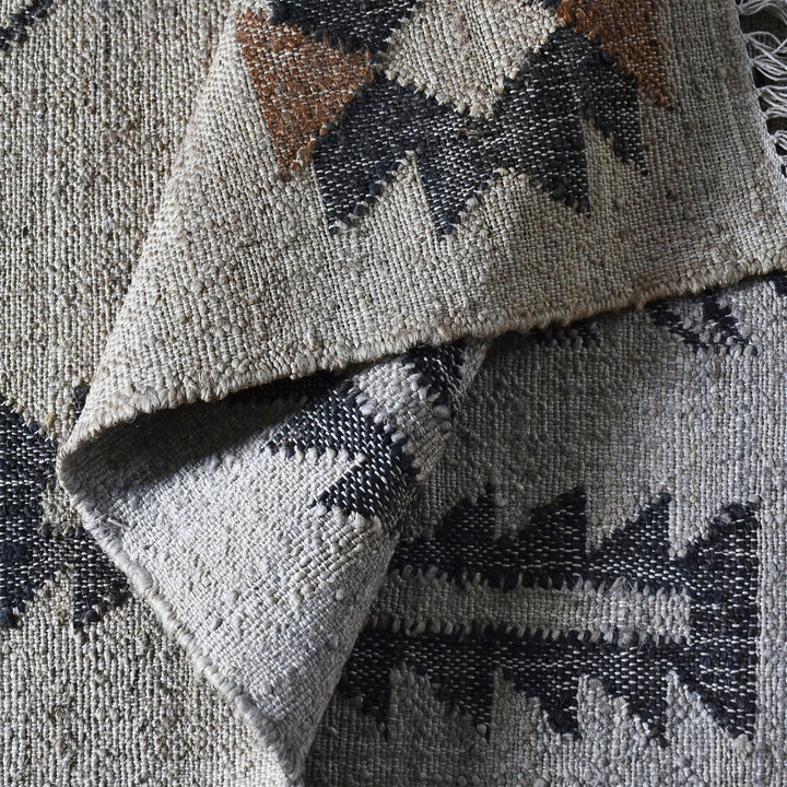 Terrain flatweave hemp rug with grey ground and terracotta and black motifs, in an entryway