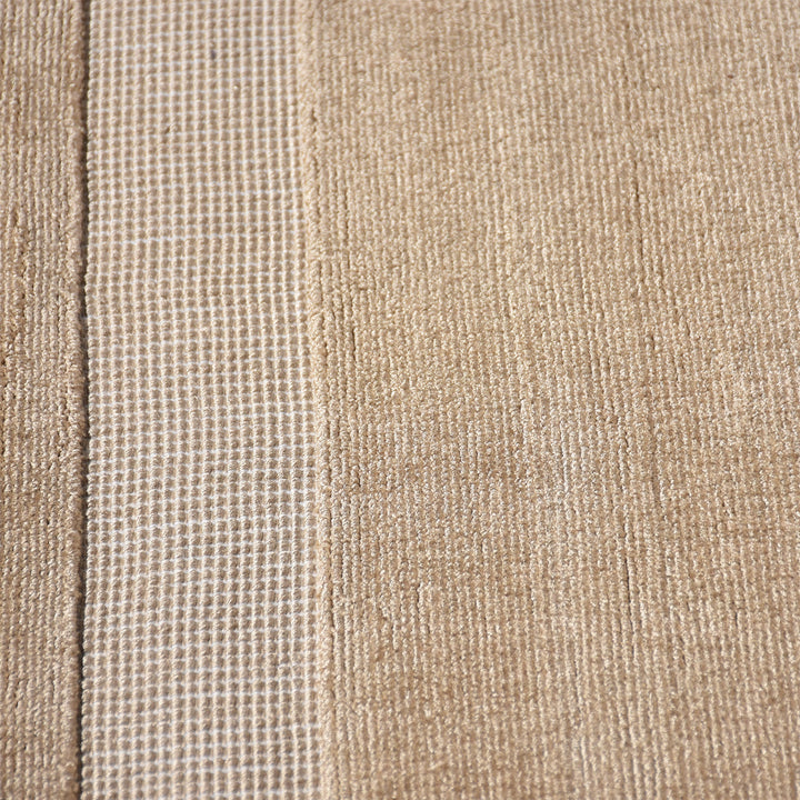 Chamak handwoven viscose rug in plain camel sand with a soft sheen, in a living room