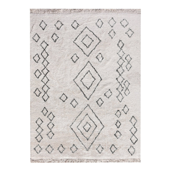 Chhapa tufted cotton rug with black diamonds and chevron borders on bone white, in a study