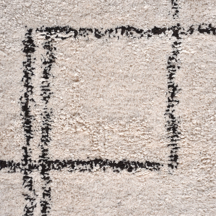 Khaka tufted cotton rug with charcoal outline squares on ivory, in a living room