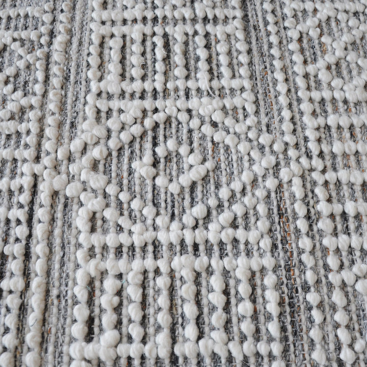 Baoli handwoven recycled PET rug with chunky ivory and grey tribal geometry, in an entryway