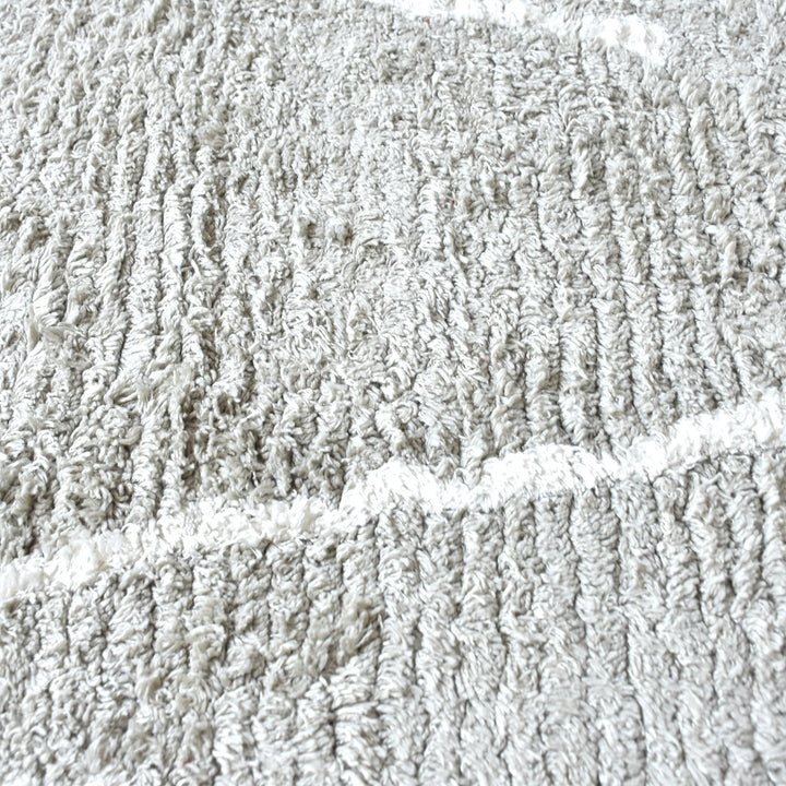 Jugnu tufted cotton and viscose rug with ivory diamond lines on silver grey, in a bedroom
