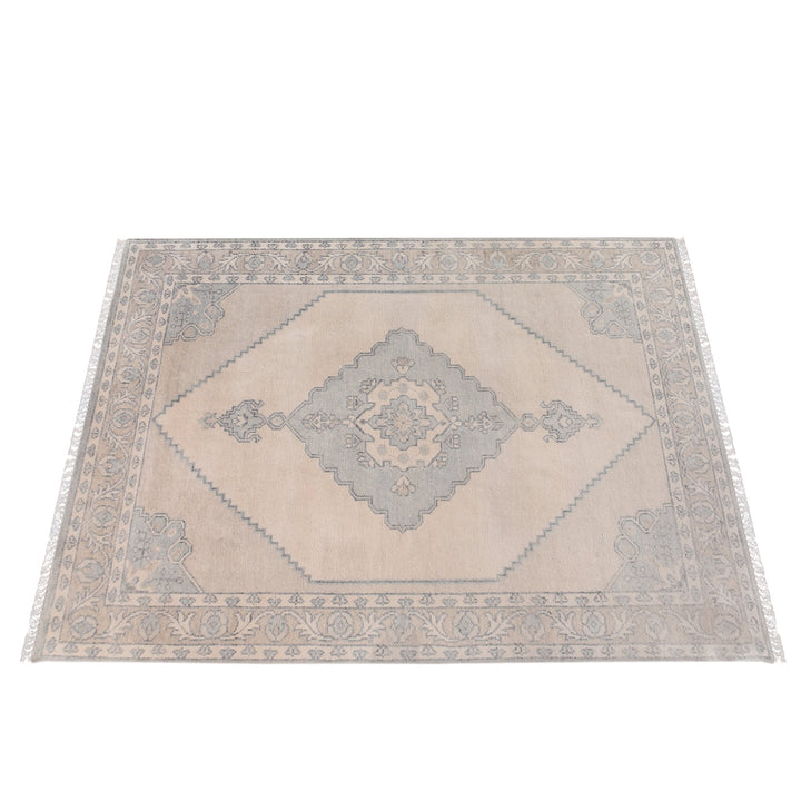 Aab hand-knotted wool rug with a faded blue medallion on an ivory ground, in a living room