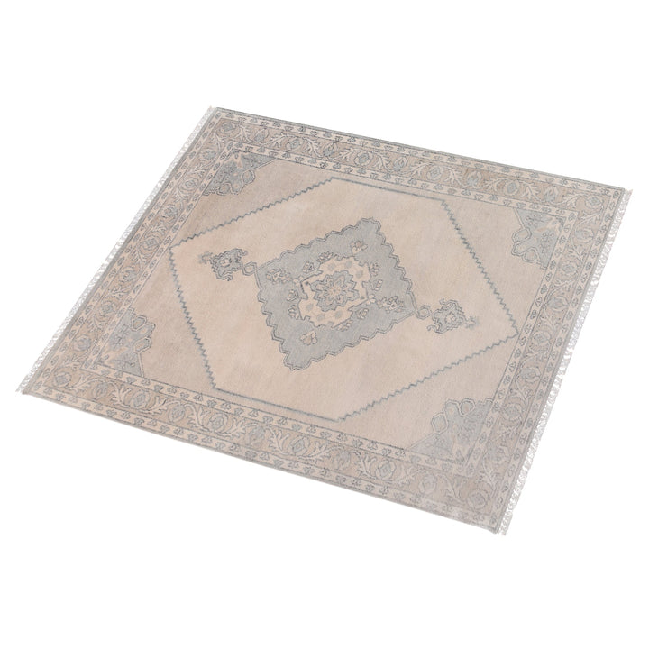 Aab hand-knotted wool rug with a faded blue medallion on an ivory ground, in a living room