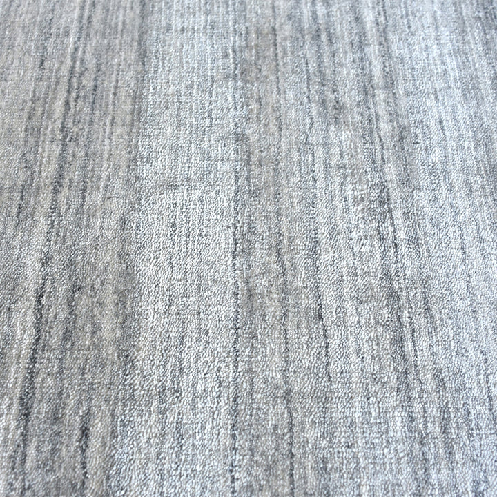 Baadal handwoven wool and viscose rug in streaked grey, charcoal and silver, in a living room