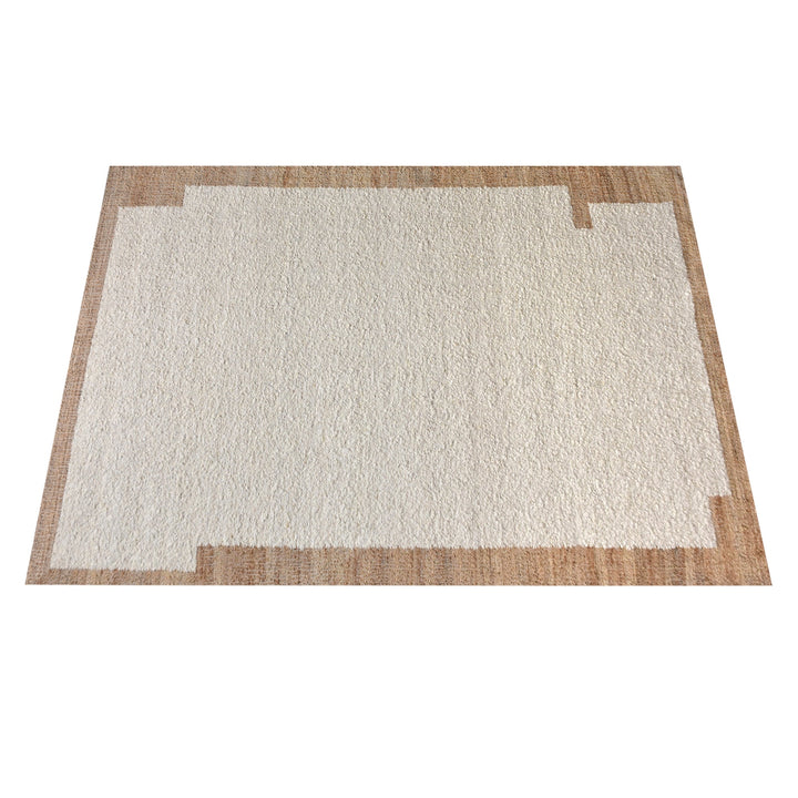 Kinari handwoven wool and jute rug in pale ivory with plain ribs and a tonal border, in a living room
