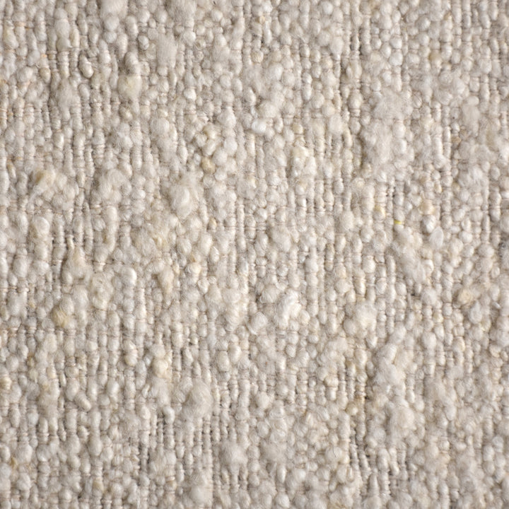 Kinari handwoven wool and jute rug in pale ivory with plain ribs and a tonal border, in a living room