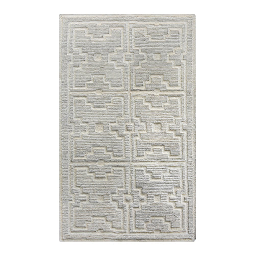 Chattan handwoven New Zealand wool rug with raised ivory diamonds on stone grey, in a living room