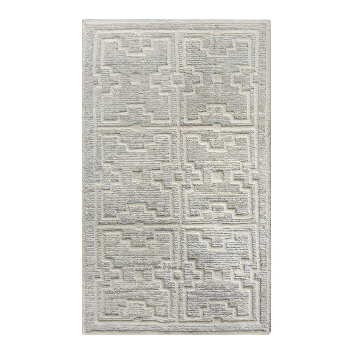 Chattan handwoven New Zealand wool rug with raised ivory diamonds on stone grey, in a living room