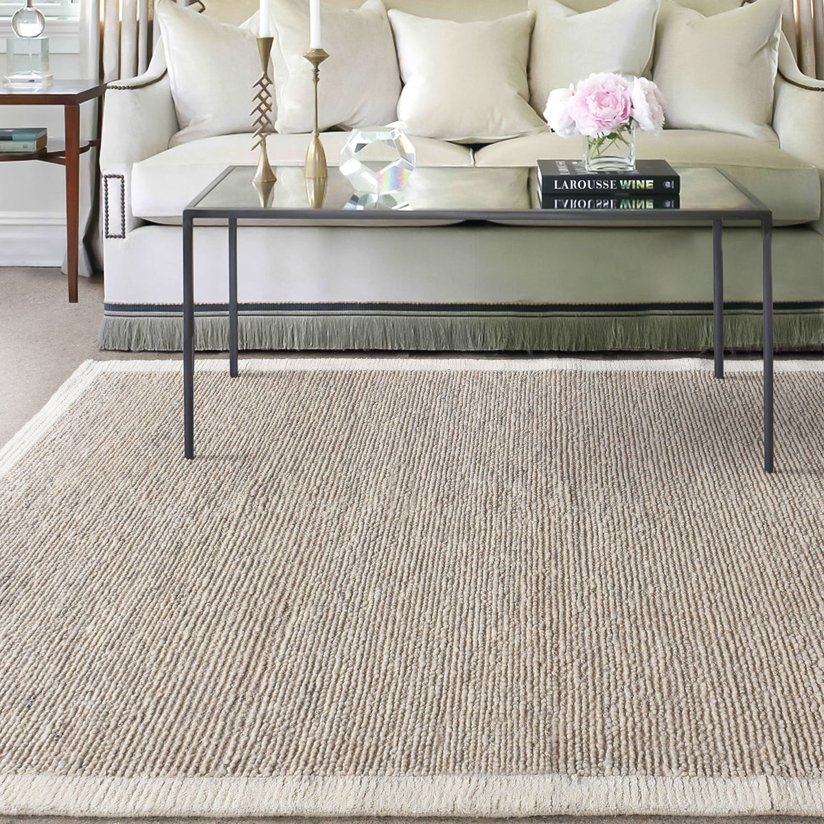 Shant handwoven flatweave wool rug in natural ivory with fine ribs and fringe, beside a bed