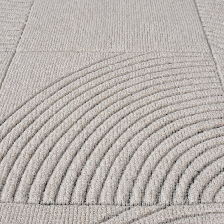 Seashell handwoven ivory wool rug with carved concentric arc tiles, in a bedroom