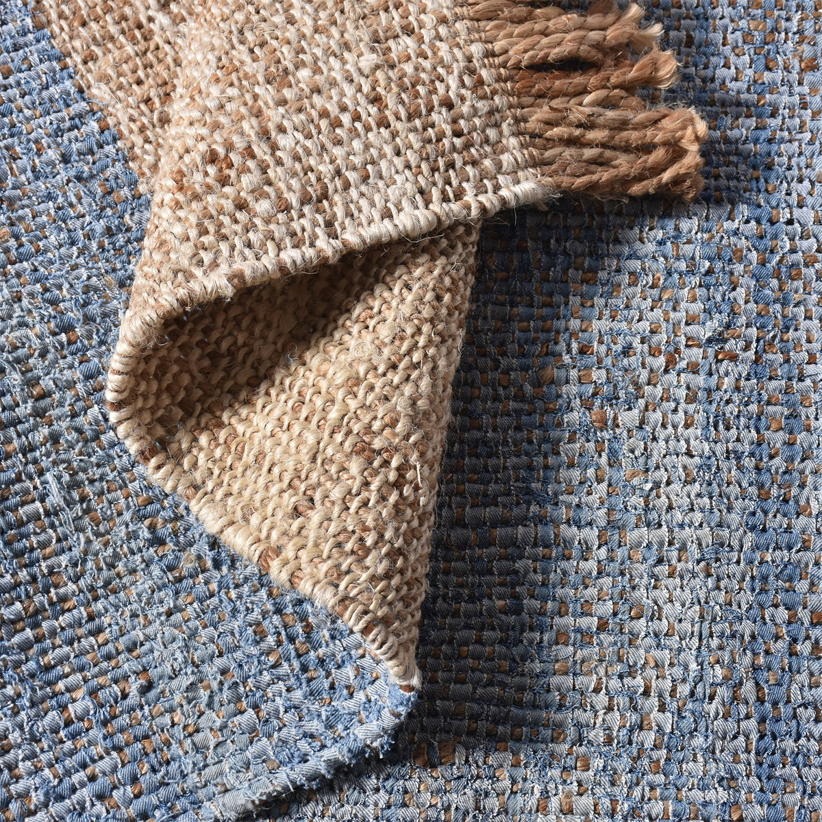 Nahar flatweave hemp and denim rug with a denim-blue stripe on natural hemp, in a living room