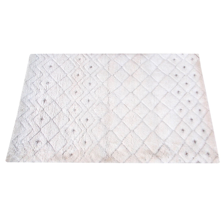 Til handwoven New Zealand wool flatweave rug with an ivory diamond lattice and dots, in a living room