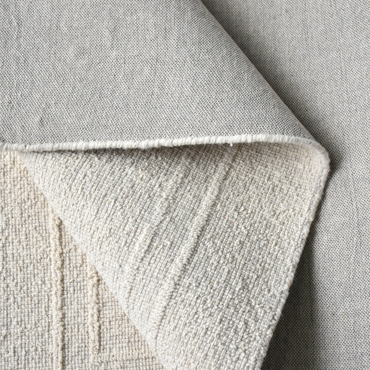 Margin handwoven ivory wool rug with a raised tonal border, in a living room