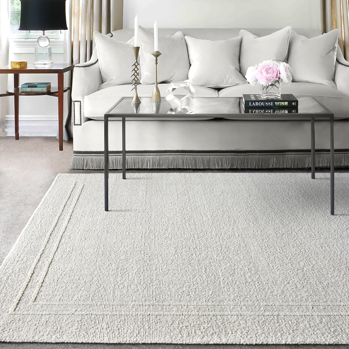 Margin handwoven ivory wool rug with a raised tonal border, in a living room