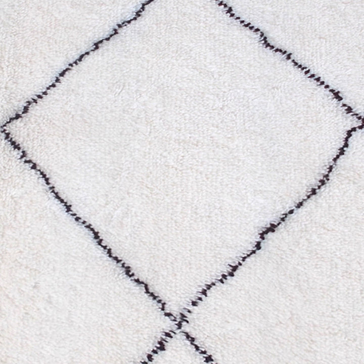 Snowfield handwoven wool rug with fine charcoal diamond lattice on ivory, in a study