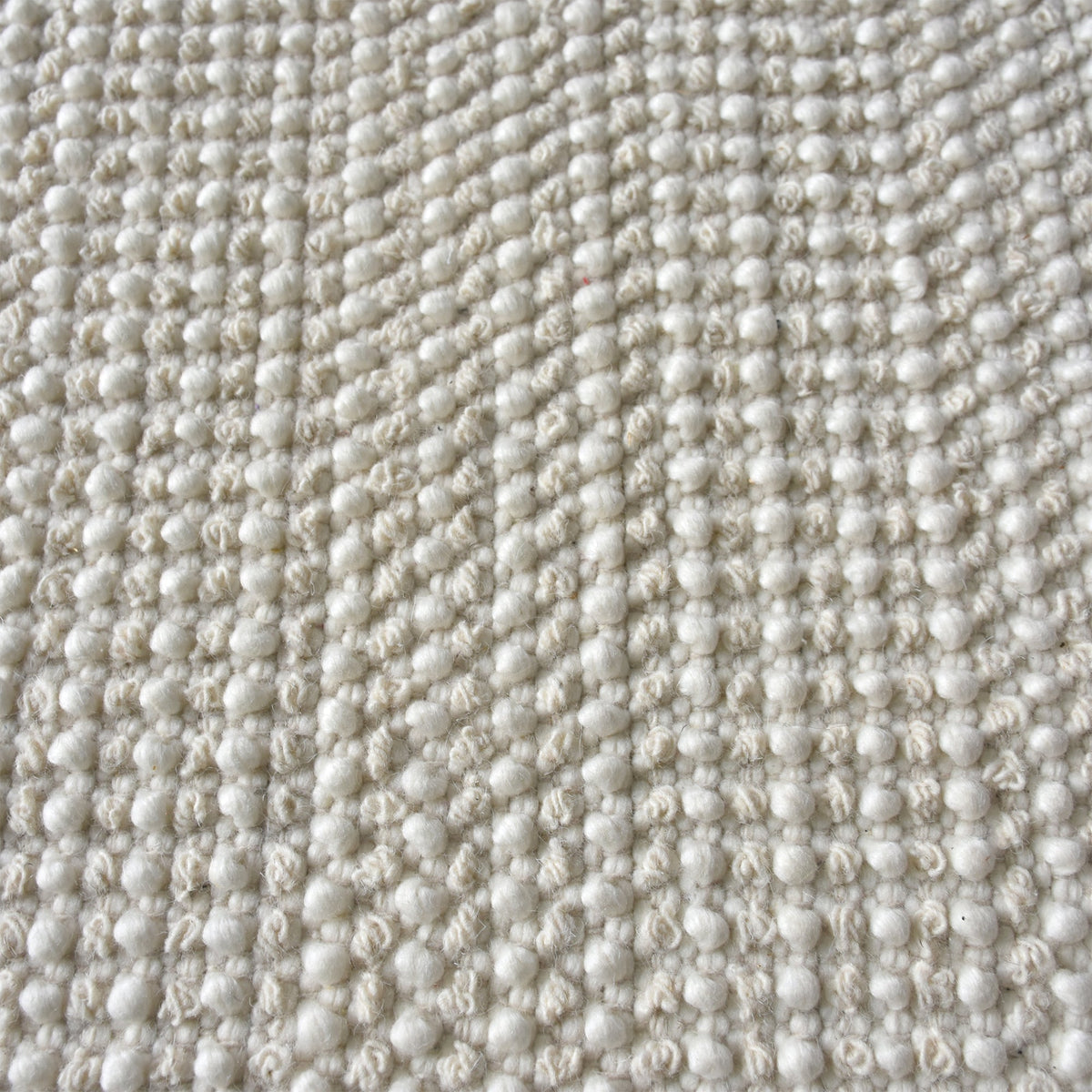 Basket handwoven cream wool rug with basketweave texture and tonal border, in a bedroom