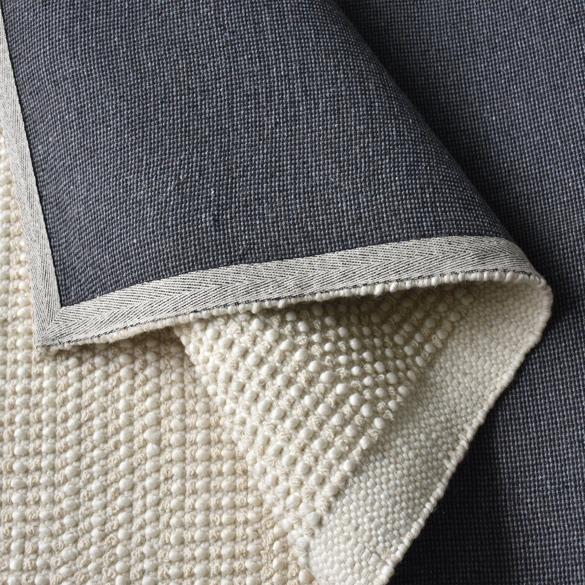 Basket handwoven cream wool rug with basketweave texture and tonal border, in a bedroom