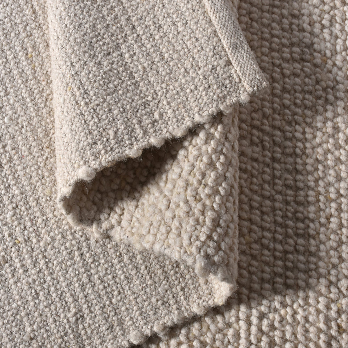 Bunai handwoven wool rug with a chunky looped bouclé surface in oatmeal, in a living room
