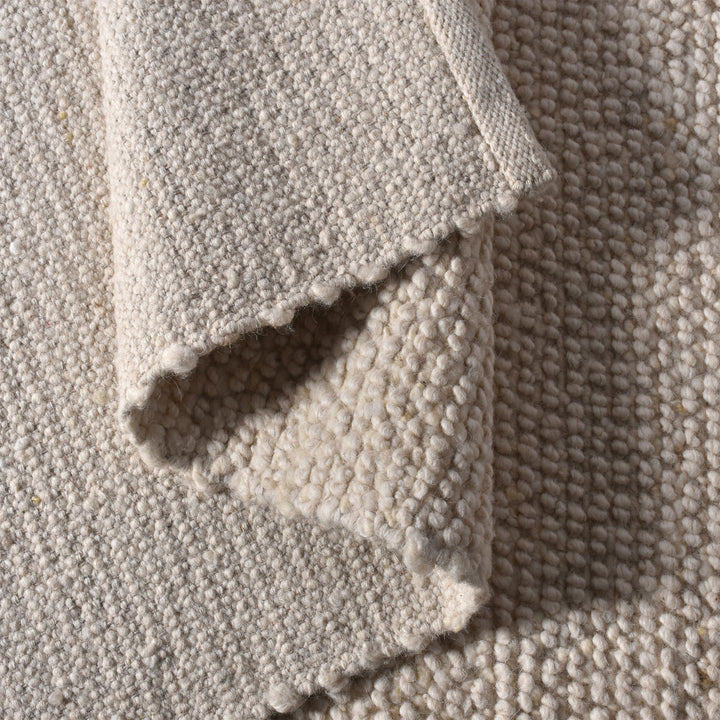Bunai handwoven wool rug with a chunky looped bouclé surface in oatmeal, in a living room