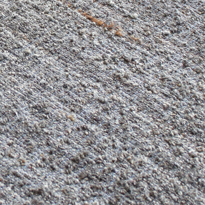 Saada handwoven flat wool rug in solid stone beige with charcoal, in a living room