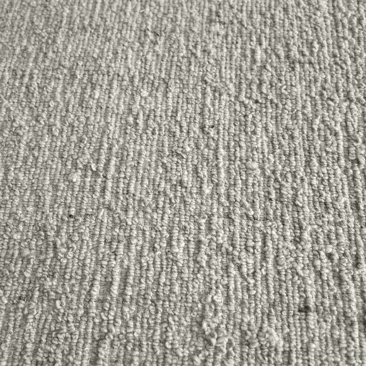 Saada handwoven flat wool rug in solid stone beige with charcoal, in a living room