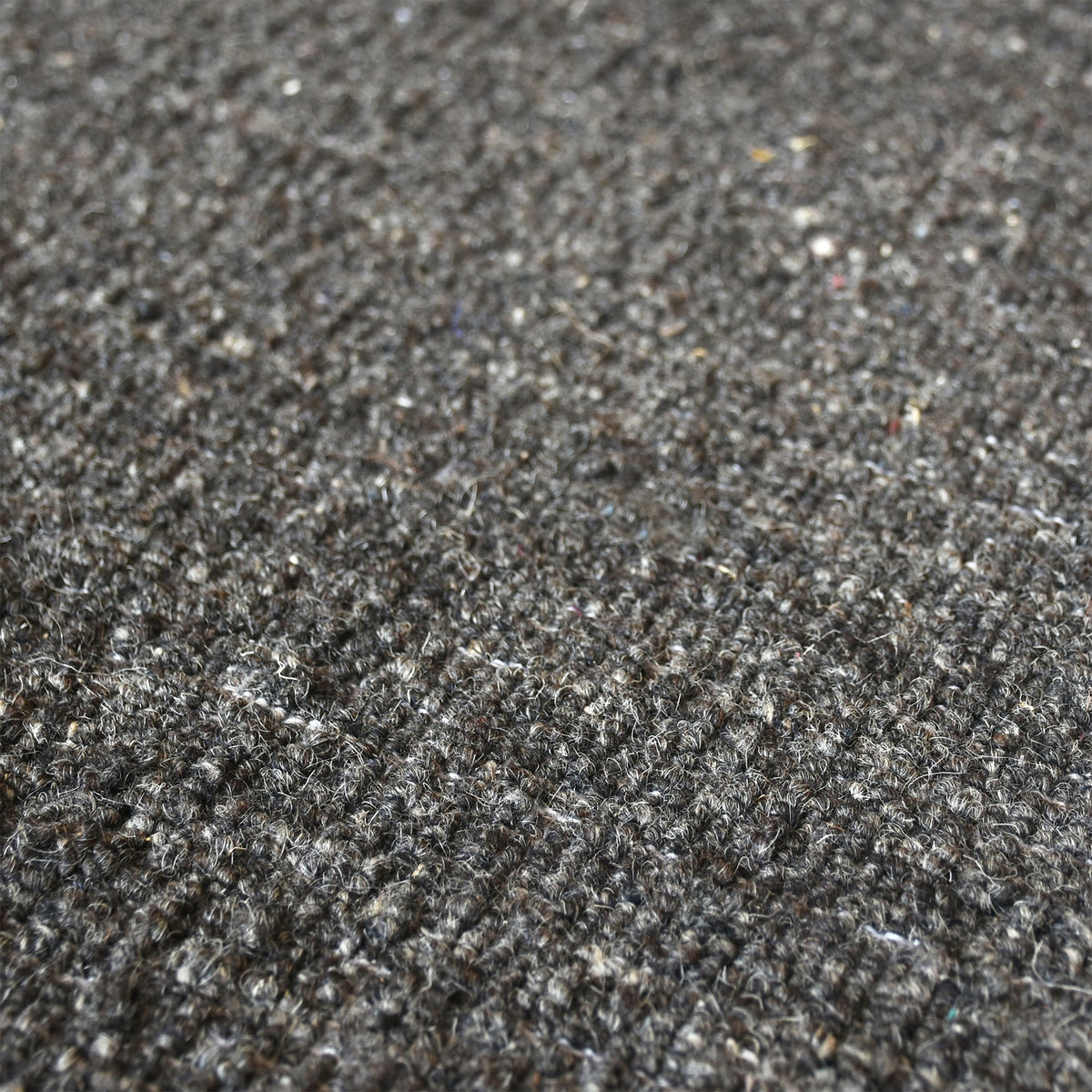 Saada handwoven flat wool rug in solid stone beige with charcoal, in a living room